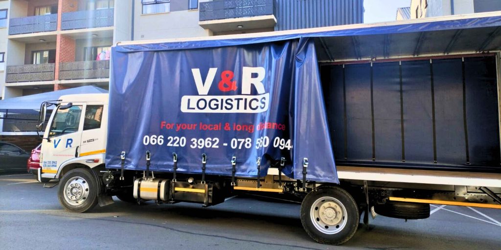 V&R Logistics white curtain-side truck with blue tarp branding, ready for local and long-distance transport services and freight delivery.